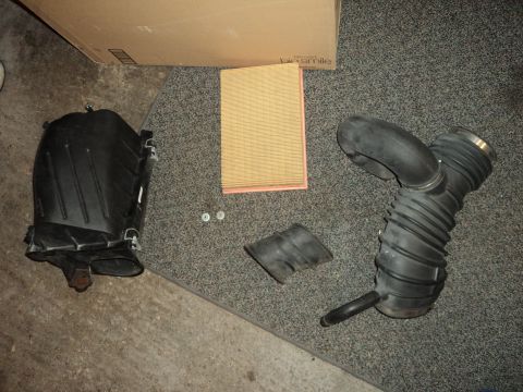2004 Mercury Grand Marquis - Air intake components and a new air filter are displayed on a carpeted surface.