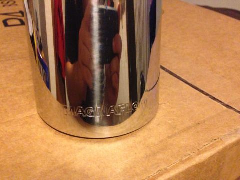 1992 Ford F-150 - A close-up view of a chrome exhaust tip, showing embossed branding, placed on a cardboard surface.