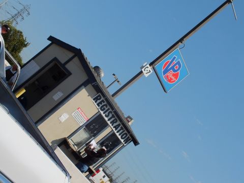 2003 Ford Crown Victoria - angled photo of an event registration building beneath a VP Racing Fuels flag, with attendees gathered at the doorway.