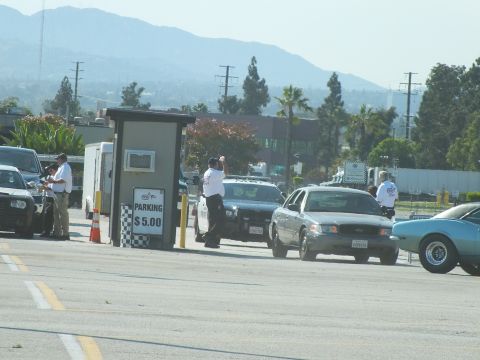 2003 Ford Crown Victoria - Attendants staff a $5.00 parking booth as sedans queue at an outdoor event with hazy mountains in the distance.