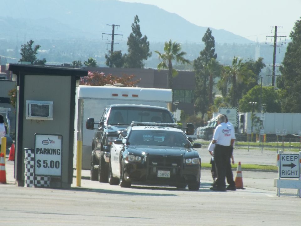 Black sedan and pickup at a $5.00 parking booth with KEEP RIGHT sign and attendants