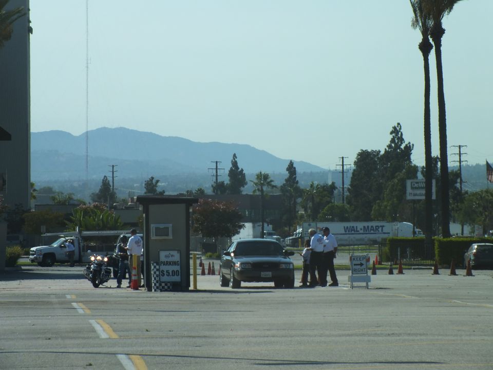 Parking entry with motorcycle, sedan and attendants, Wal-Mart sign and mountains behind