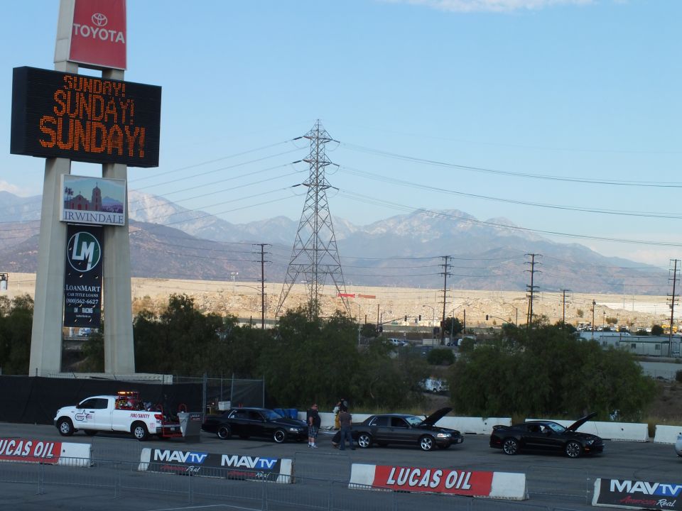 Illuminated SUNDAY message sign atop a Toyota pylon over a drag staging lane and mountains