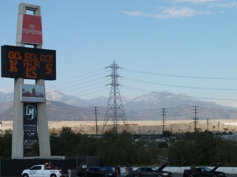 2003 Ford Crown Victoria - tall Toyota and Irwindale pylon sign with a scrolling LED display towers over staged cars and distant mountains.
