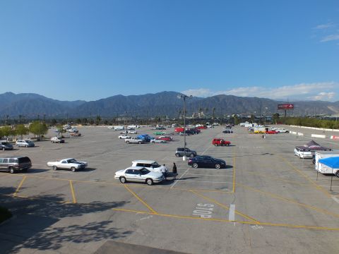 2003 Ford Crown Victoria - Elevated wide view of an event lot dotted with classic and modern cars and a white El Camino, mountains in the distance.