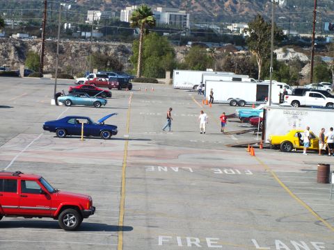 2003 Ford Crown Victoria - From above, classic coupes including a blue one with hood up, a red Jeep and enclosed trailers fill a FIRE LANE lot.