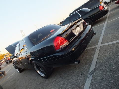 2003 Ford Crown Victoria - Close low-angle rear three-quarter shot of a black full-size sedan's trunk and taillight.