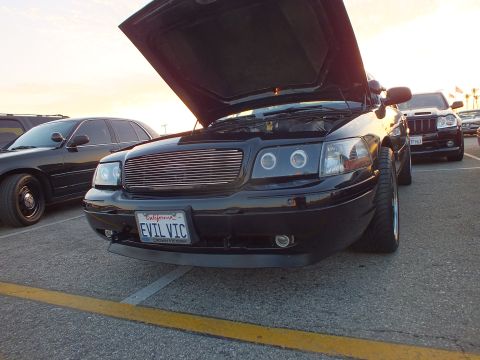2003 Ford Crown Victoria - Low front view of a black Ford Crown Victoria with halo headlights and a California 'EVIL VIC' plate.
