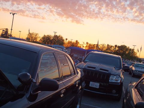 2003 Ford Crown Victoria - Vehicles crowd a parking lot at sunset, including a black SUV with a hood scoop, its front plate reading 7BTF263.