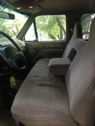 1986 Ford Bronco - The interior of a 1992 Ford F-150 features cloth seats and a central armrest.