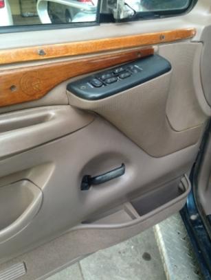 1986 Ford Bronco - Close-up of a vehicle's interior door panel, showing wood trim and power window controls.