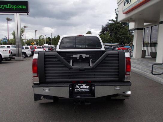 2001 Ford F-350 pickup truck rear view with gooseneck hitch installed in bed. Other trucks are parked in background