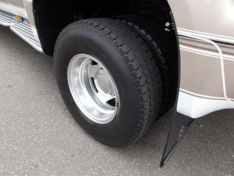 2001 Ford F-350 - Close-up view of the rear dually wheels and fender of a tan and white truck.