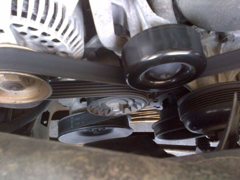1994 Ford Bronco - A close-up view of the serpentine belt and pulleys in an engine bay.