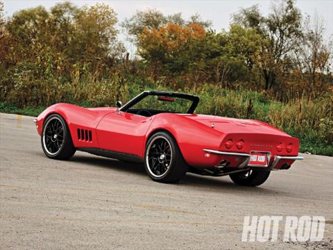 1976 Chevrolet Corvette - Red convertible sports car parked on a paved road with trees in the background.