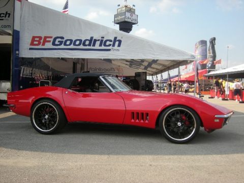 1976 Chevrolet Corvette - A red convertible sports car is parked under a tent with BFGoodrich branding.