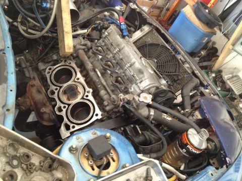 1995 Ford Probe - A disassembled engine sits in a garage, surrounded by tools and spare parts.