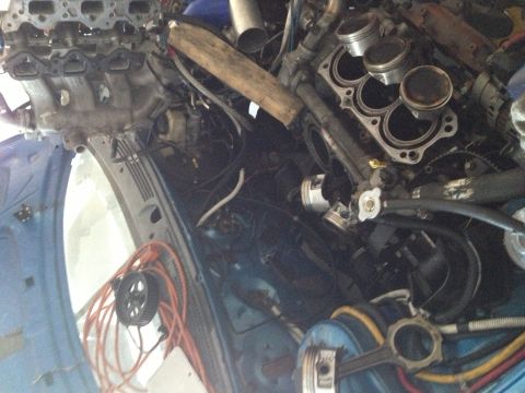 1995 Ford Probe - The engine bay of a blue vehicle is shown disassembled with various engine parts exposed.