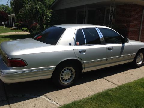 1995 Mercury Grand Marquis - A silver 1995 Mercury Grand Marquis is parked in a suburban driveway, showing its side profile.