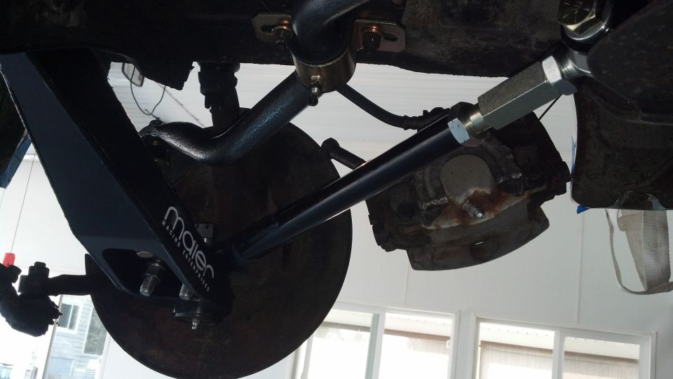 Aftermarket suspension component with Maier Racing logo, attached to a brake rotor and chassis