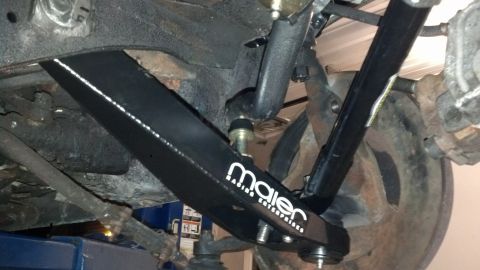 1970 Ford Torino - Close-up of aftermarket suspension parts, including a control arm, on a vehicle's undercarriage.