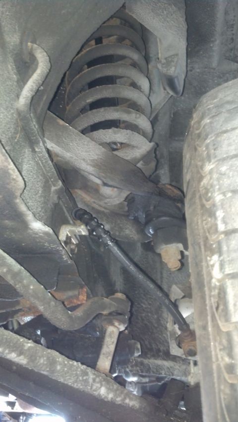 1970 Ford Torino - Underside view of a vehicle's suspension system, showing a coil spring and linkage components.