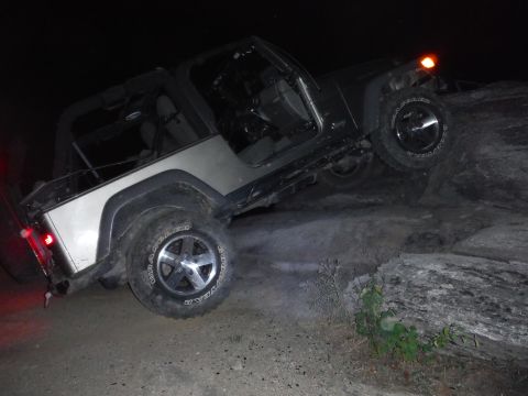 2005 Jeep Wrangler - A Jeep Wrangler navigates a rocky terrain in the dark, with its doors removed.