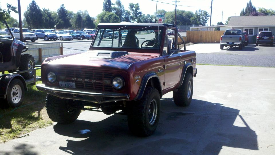 Red Ford Bronco with roll cage and aftermarket wheels