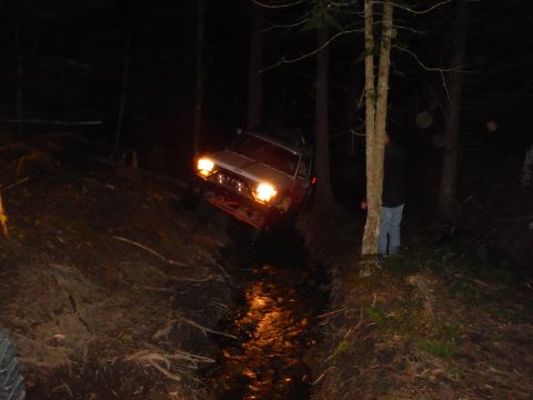 2005 Jeep Wrangler - A 2005 Jeep Wrangler navigates a wooded trail at night, its headlights illuminating the path.