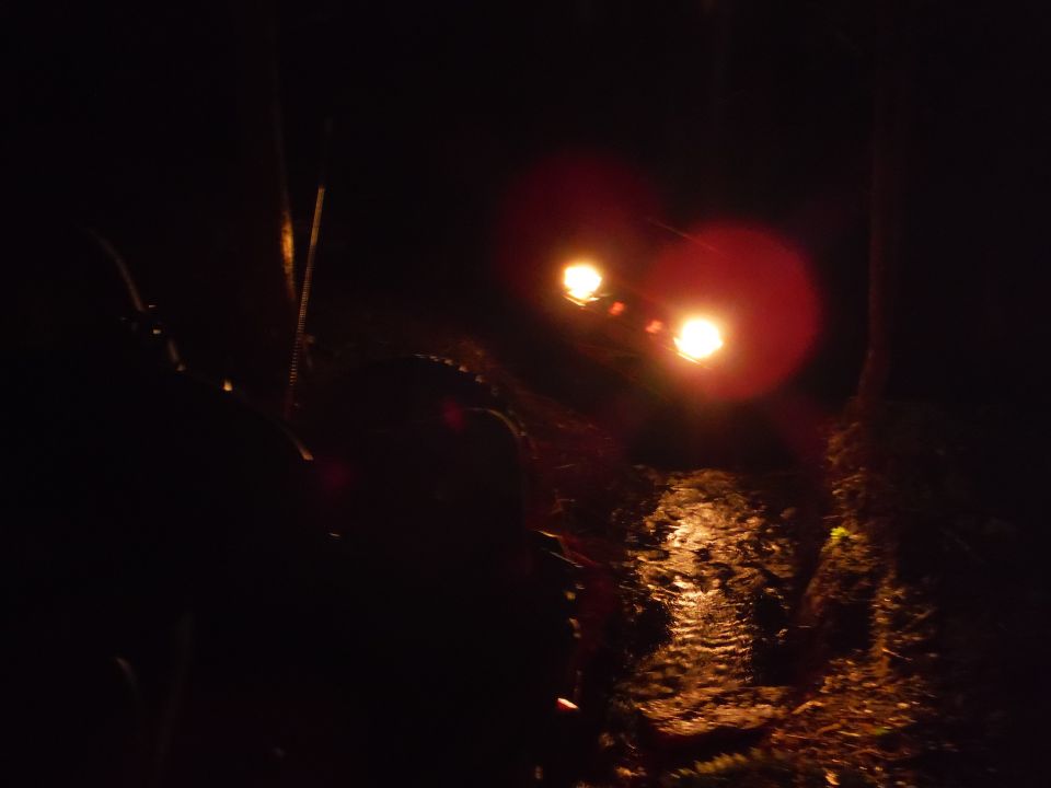 2005 Jeep Wrangler headlights illuminated at night, reflecting on wet ground