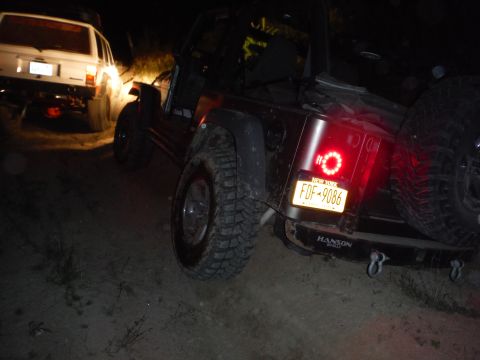 2005 Jeep Wrangler - A dark Jeep Wrangler is seen from the rear at night, with a white Jeep Cherokee in the background.