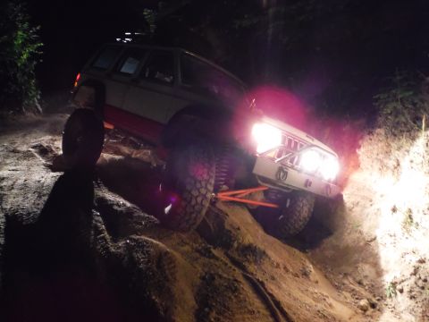 2005 Jeep Wrangler - This off-road vehicle navigates a challenging rocky terrain under the cover of darkness, its headlights cutting through the night.