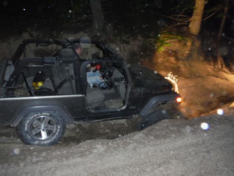 2005 Jeep Wrangler - A black Jeep Wrangler Rubicon navigates a challenging off-road trail in the dark.