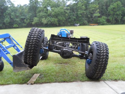 1992 Ford Bronco - The chassis of a vehicle, large off-road tires and a blue engine, is shown from the front. A Supermotors.net logo is visible in the lower r…