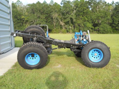 1992 Ford Bronco - The frame and powertrain of a custom off-road vehicle are shown, sitting on large tires.