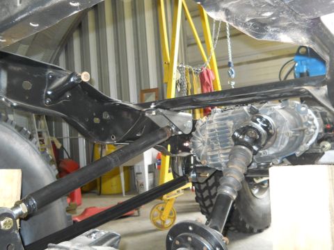 1992 Ford Bronco - Close-up of a vehicle's undercarriage, focusing on the transfer case and driveshaft assembly. The SuperMotors.net logo is present in the lo…