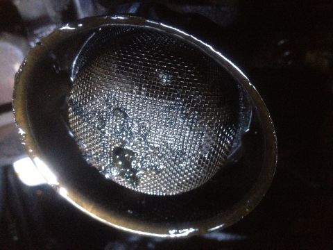 1978 Ford Bronco - Close-up view of a dirty oil strainer, indicating potential engine issues.