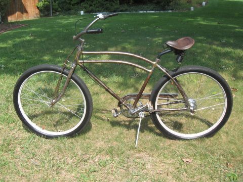 Rusty vintage bicycle with brown leather seat and white-rimmed wheels on grassy lawn