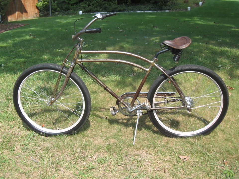 Rusty vintage bicycle with brown leather seat and white-rimmed wheels on grassy lawn