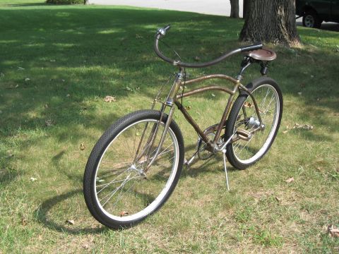Old bicycle with brown frame and seat, parked on grass