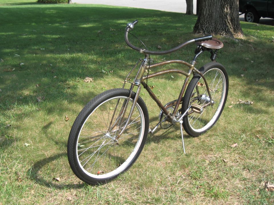 Old bicycle with brown frame and seat, parked on grass