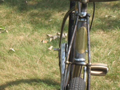 Bicycle front fork with a golden oval badge and a pedal