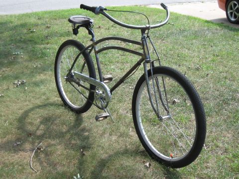 Gray bicycle with wide handlebars and a spring seat, parked on grass
