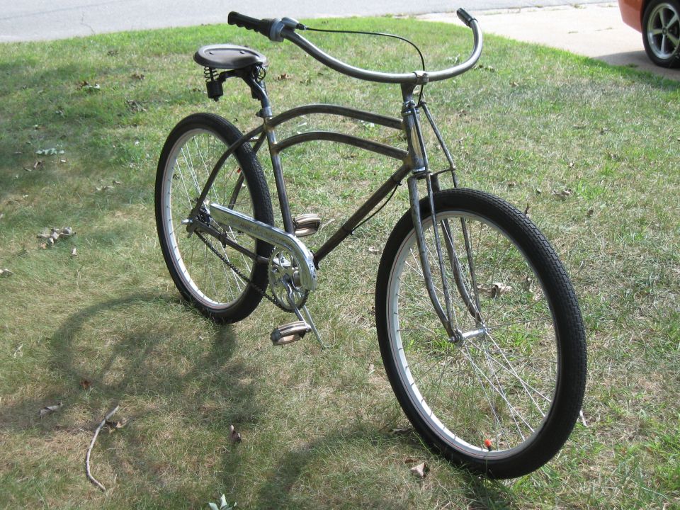 Gray bicycle with wide handlebars and a spring seat, parked on grass