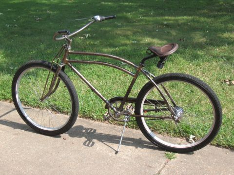 Rusty cruiser bicycle with brown leather seat and wide handlebars parked on a sidewalk