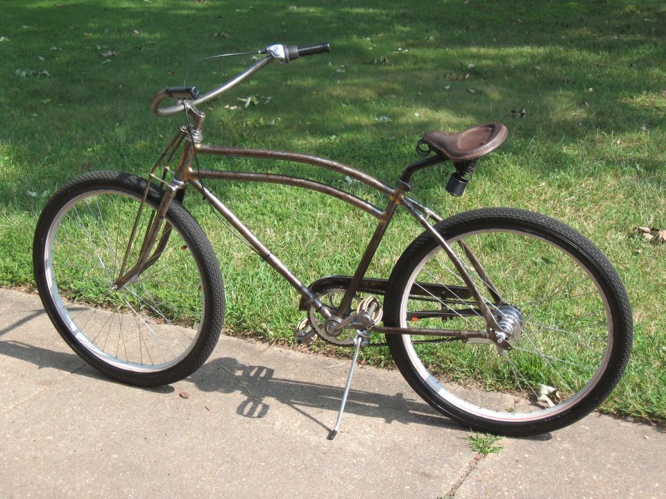 Rusty cruiser bicycle with brown leather seat and wide handlebars parked on a sidewalk