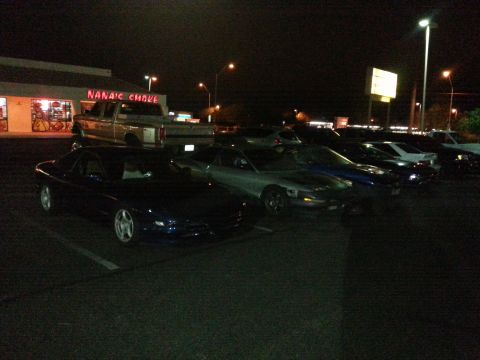 1995 Ford Probe - Several cars are parked in a lot at night, with a pickup truck and a building in the background.