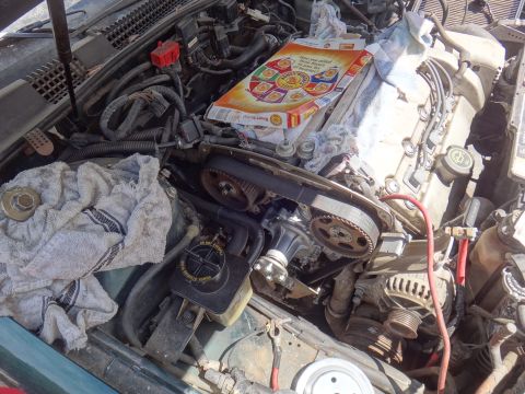 1995 Ford Taurus - Engine bay with a cereal box on top of engine components and rags.