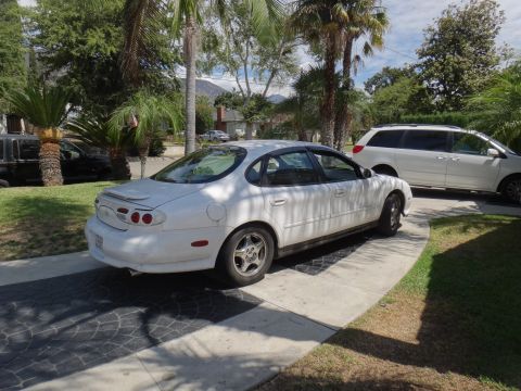 1995 Ford Taurus - A white sedan is parked on a driveway next to a white minivan.