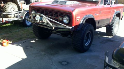 1970 Ford Bronco - A red 1970 Ford Bronco is shown from a 3/4 front angle, equipped with off-road tires and a custom bumper.